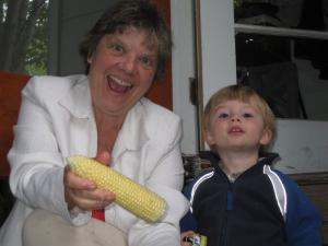 Gramma Mia and Sylvan pose while shucking corn on the back step