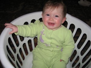 Elena in a laundry basket at six months old. Note her signature tongue flip.